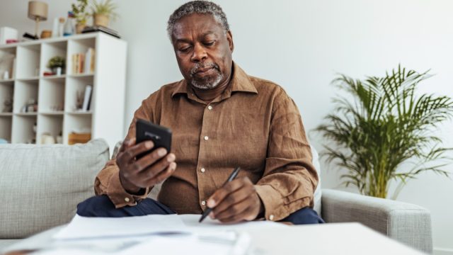 Mature businessman working at home using smart phone