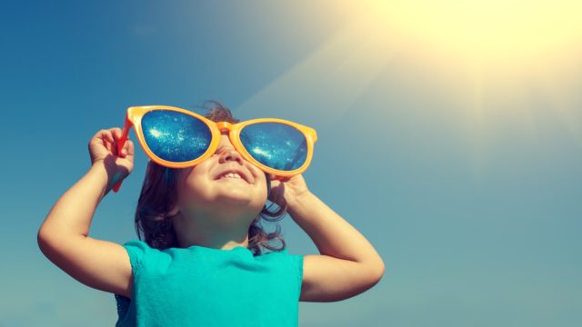 happy little girl with big sunglasses looking at the sky