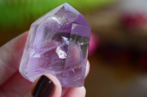 A woman's hand holding a light amethyst tower