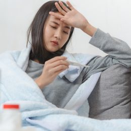 young asian woman taking her temperature and feeling sick