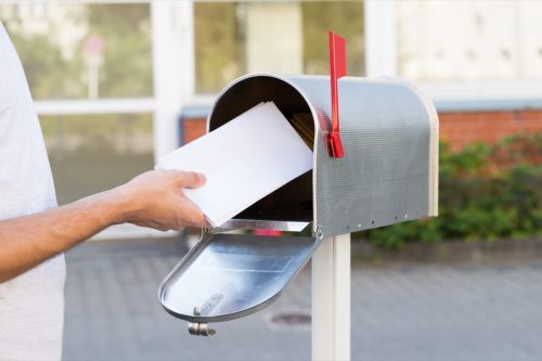 person putting a letter in the mailbox