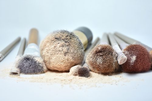 an assortment of makeup brushes covered with powder on a white background