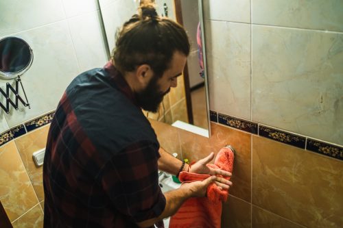 Bearded man drying his hands in the bathroom at home
