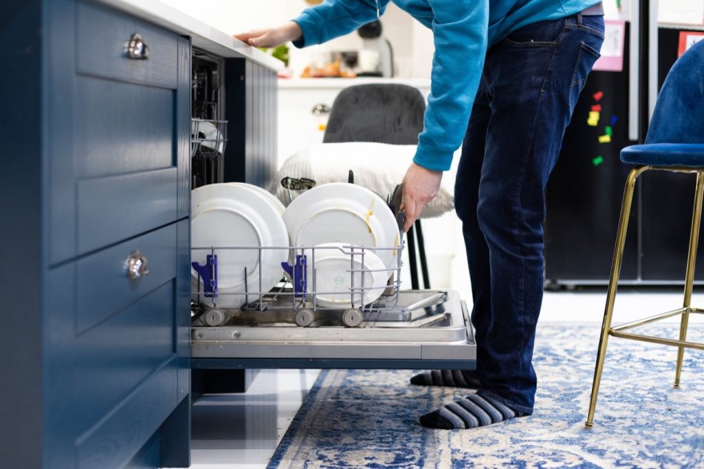 man filling up dishwasher with dirty dishes