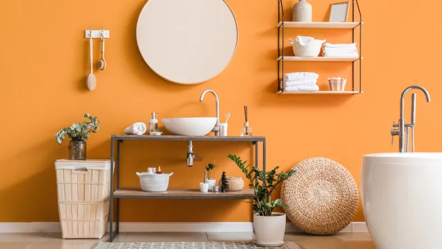 bathroom with round mirror and orange walls