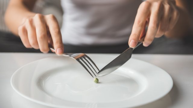 Cropped image of girl trying to put a single pea on her fork