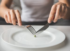 Cropped image of girl trying to put a single pea on her fork