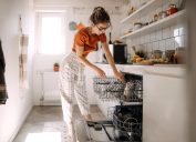 Young woman putting dishes in dishwashing machine