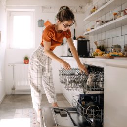 Young woman putting dishes in dishwashing machine