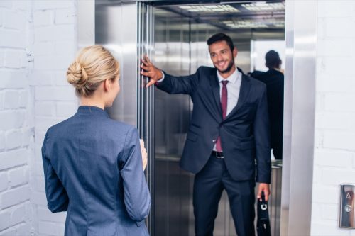 man holding elevator door for coworker
