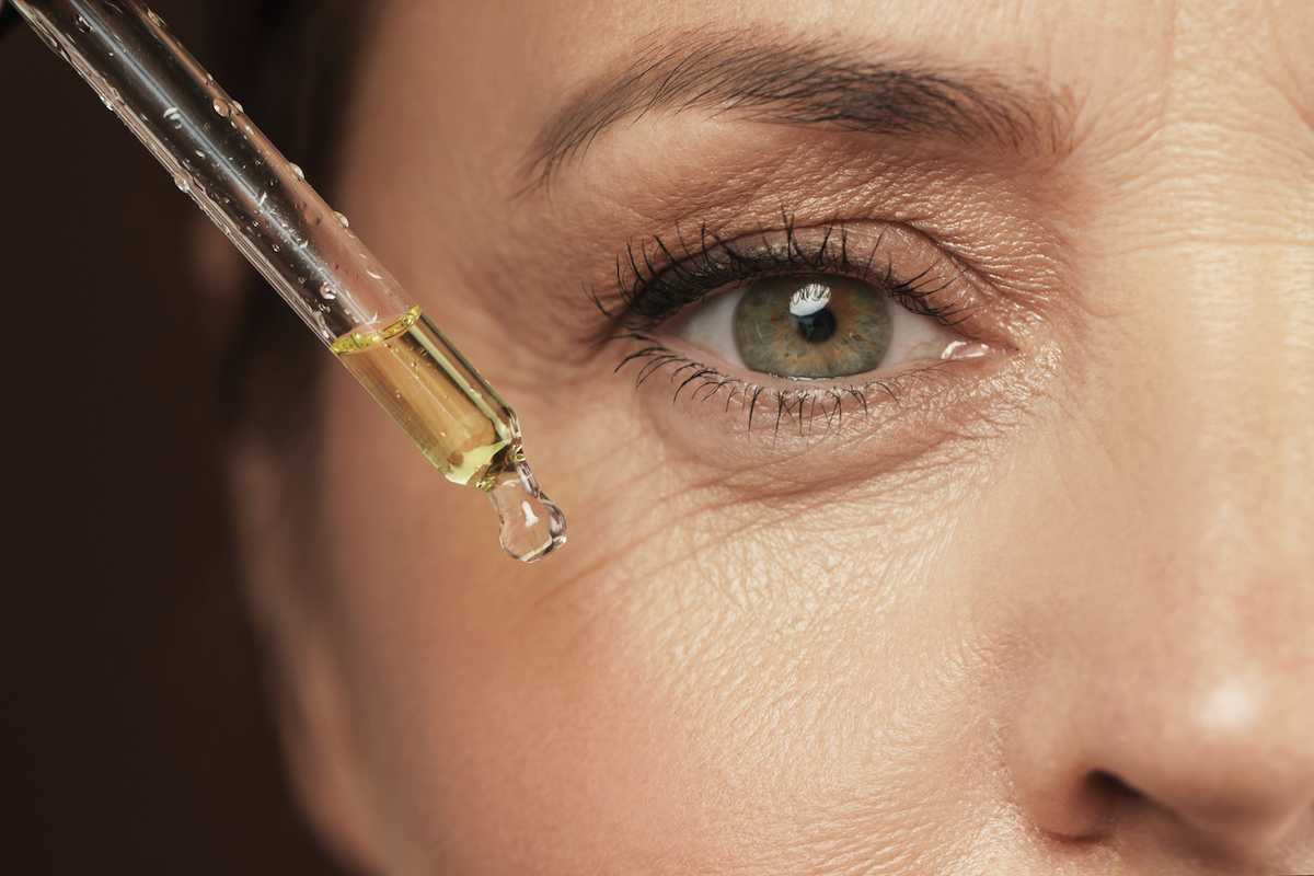 Closeup of female eye and dropper with rejuvenating serum