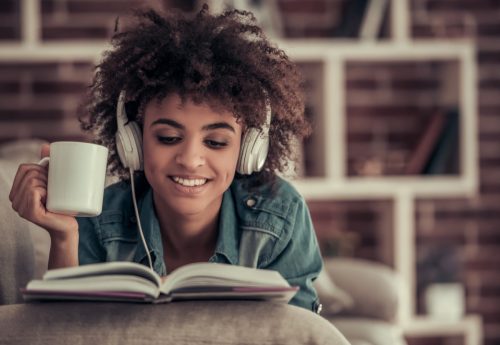 woman wearing headphones while reading inspirational quotes out of a book