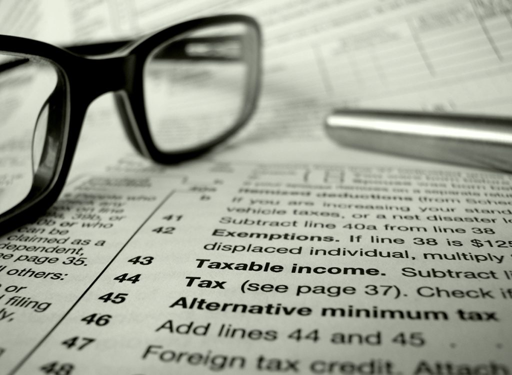 Glasses and pen laying on tax papers