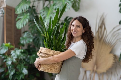 woman smiling holding houseplant