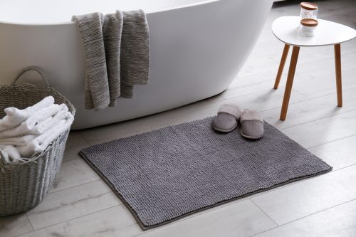 bathroom with soaking tub, mat and grey towel