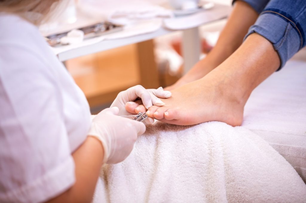 Nail tech clipping a woman's toenails during a pedicure