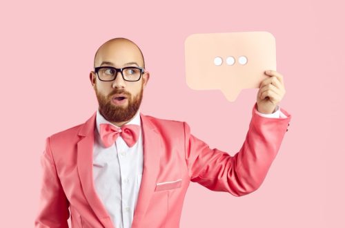 man in pink suit holding up a texting ellipsis