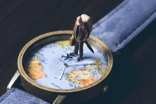 figurine standing on top a watch-face with a world map