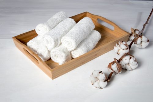 A wooden tray with rolled hand towels stacked in it