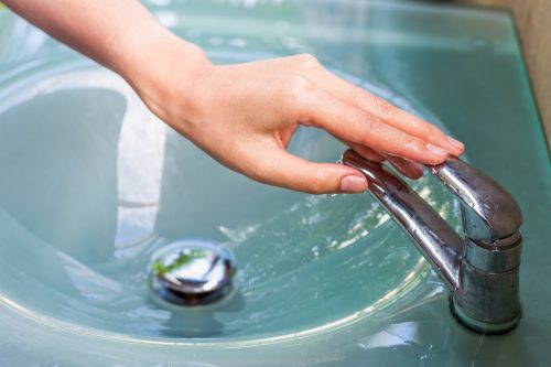woman turning faucet off with her hand