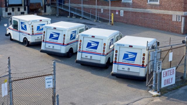 Postal vehicles parked in post office lot at Haverhill Massachusetts, September 2022. A typical busy post office lot where trucks load and unload postal mail distributed around the world.