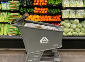 Product image of an Albertson's smart shopping cart made by Veeve in front of a produce display