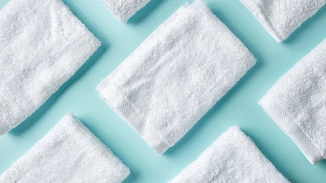 White spa towels on light blue background, top view