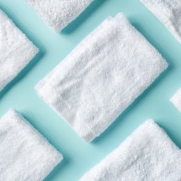 White spa towels on light blue background, top view