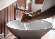 Crop close up of black man washing hands in water from tap