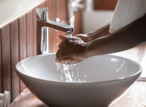 Crop close up of black man washing hands in water from tap