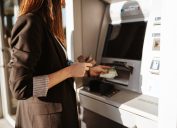 Young woman using outdoor cash machine on sunny spring day