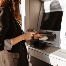Young woman using outdoor cash machine on sunny spring day