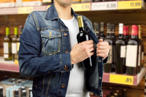 man in a supermarket stealing a bottle of champagne