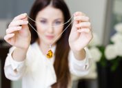Woman holding a yellow sapphire necklace up to the camera