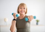 Người phụ nữ cao tuổi mạnh mẽ tập thể dục với quả tạ trong nhà.