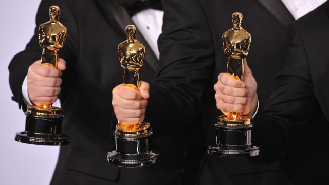 Men holding Oscar statuettes