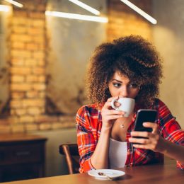 Woman Drinking Coffee While on Her Phone