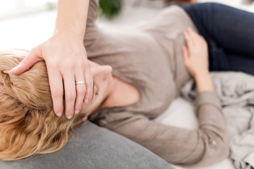 A woman lying on the couch with a headache