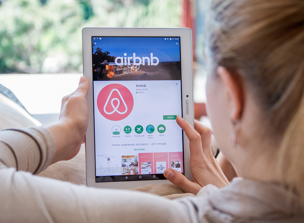 Woman holding iPad looking at Airbnb website