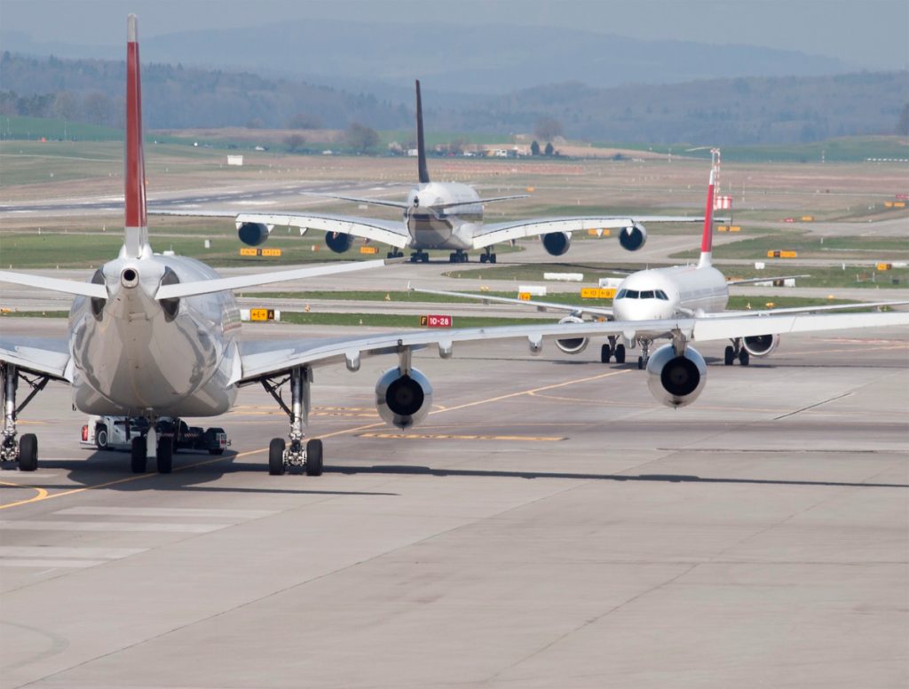 Three airplanes sitting on the runway in heavy airport traffic