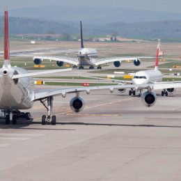Three airplanes sitting on the runway in heavy airport traffic