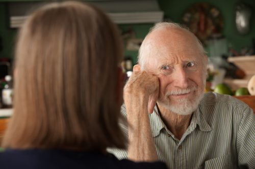 older man looking annoyed while speaking to a woman from across the table