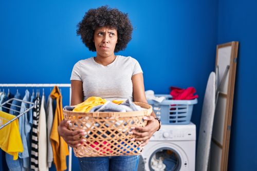 woman looking confused as she carries a basket of laundry
