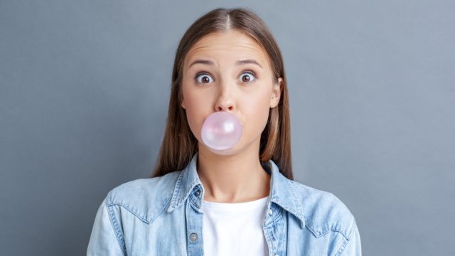 young woman chewing gum and blowing a bubble