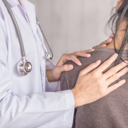 female doctor examining a patient suffering from neck and shoulder pain