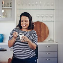 Shot of a young woman eating yogurt at home