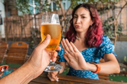woman rejecting a beer from a man at a bar
