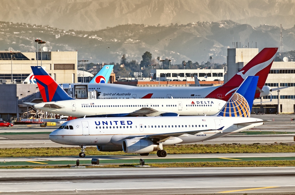 A United plane and Delta plane on the runway at a busy airport