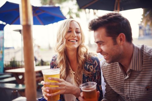 man and woman laughing over drinks at a bar