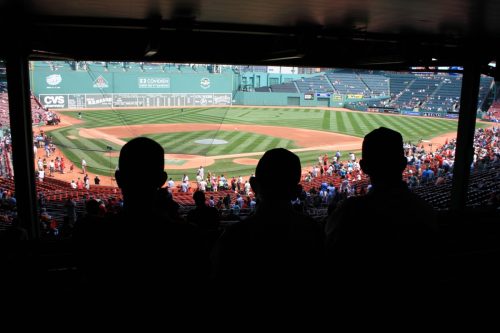 Father and sons watching a baseball game at Fenway Park in Boston.